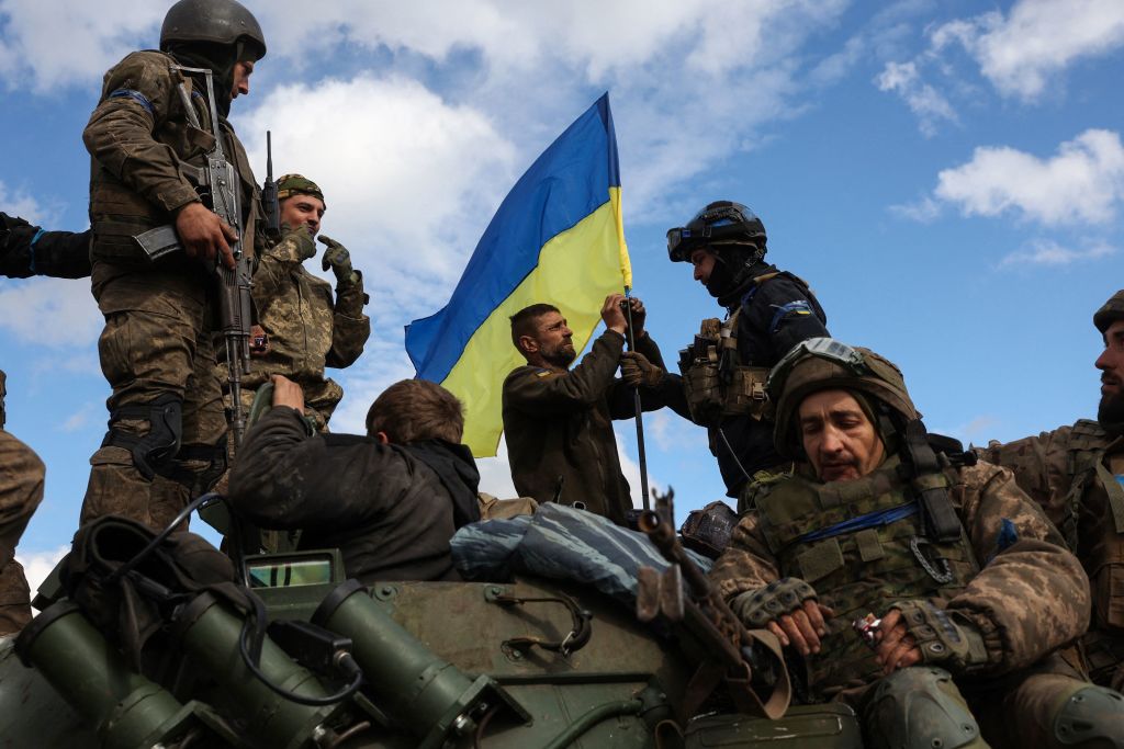 Ukrainian soldiers adjust a national flag atop a personnel armoured carrier on a road near Lyman, Donetsk region on October 4, 2022, amid the Russian invasion of Ukraine. (Photo by ANATOLII STEPANOV/AFP via Getty Images)