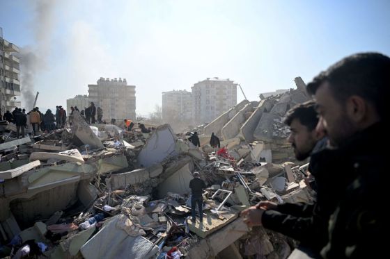 Families of victims stand as rescue officials search among the rubble of collapsed buildings in Kahramanmaras, on February 9, 2023. (Photo by Ozan Kose/AFP/Getty Images.) 