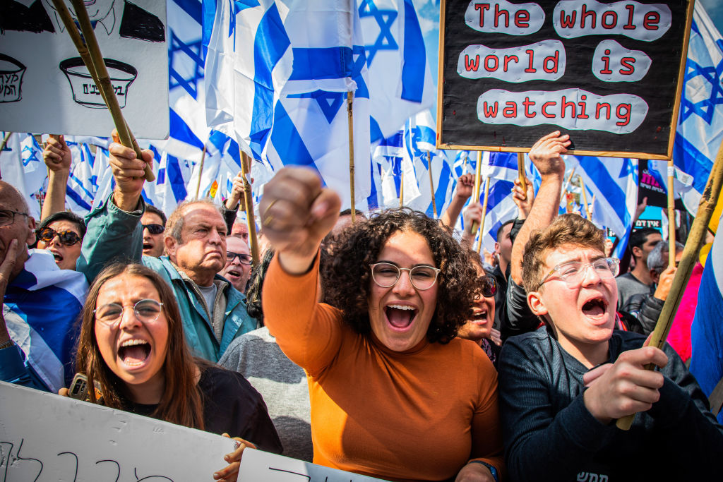 Protesters hold Israeli flags and placards while chanting