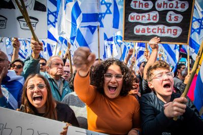 Protesters hold Israeli flags and placards while chanting