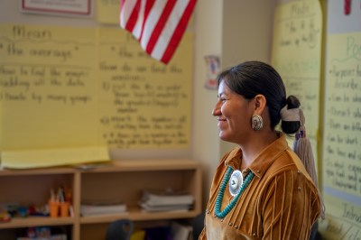 Smiling Young Woman Teacher at the Front of Her Classroom Engaging and Teaching Her Young Students