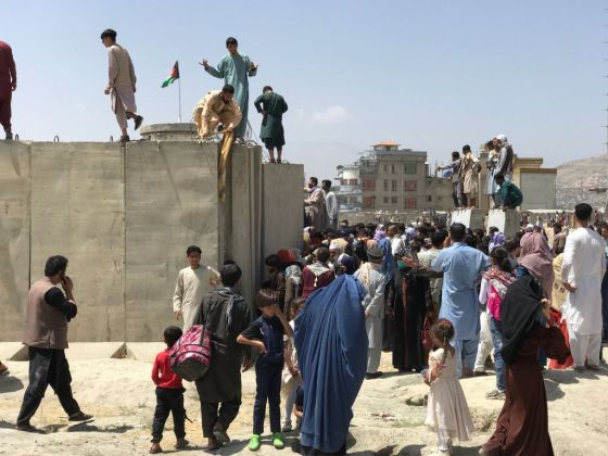 People struggle to cross a boundary wall at the Kabul International Airport to flee Afghanistan on August 16, 2021. (Photo by STR/NurPhoto via Getty Images)