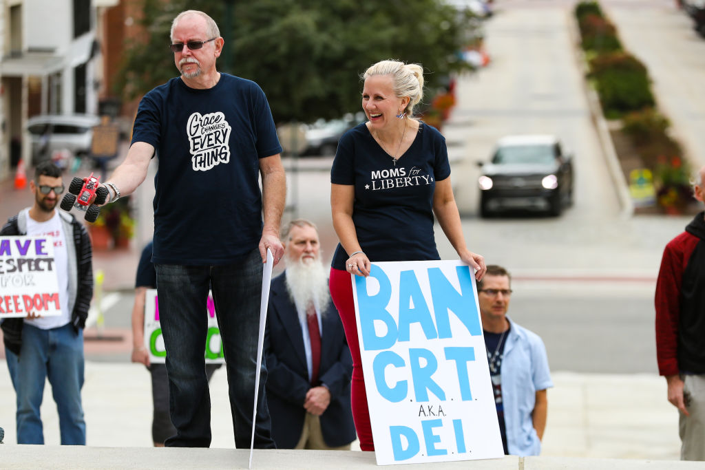 Protesters hold placards at a Moms for Liberty rally at the
