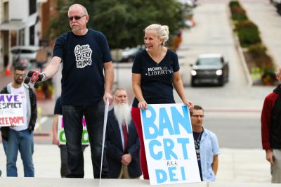 Protesters hold placards at a Moms for Liberty rally at the