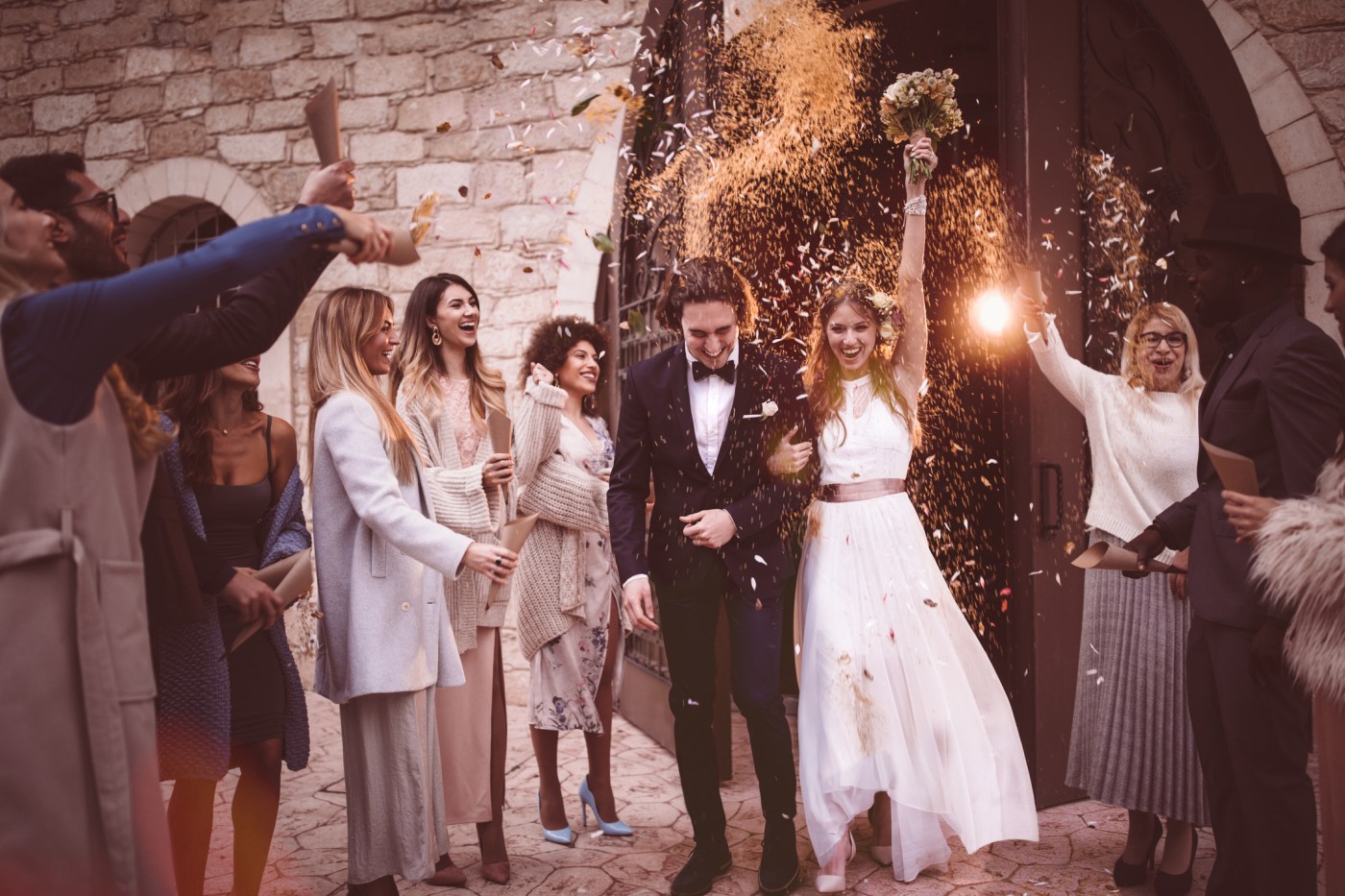 Newlywed couple walking out church and celebrating wedding with confetti