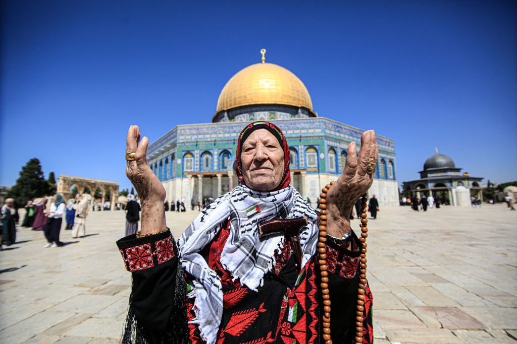 An elderly Palestinian lady offers her prayers as she