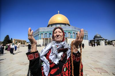 An elderly Palestinian lady offers her prayers as she
