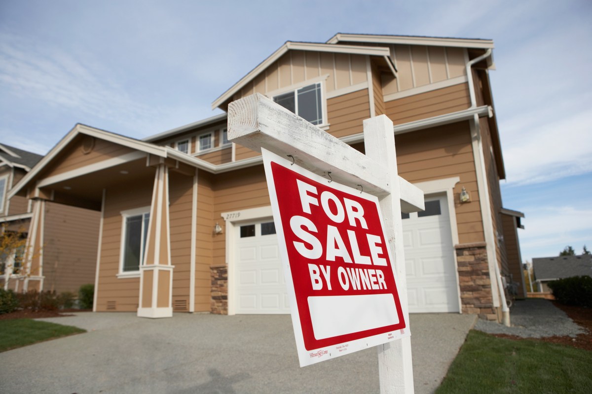 ‘For Sale’ sign in front of house (focus on sign)