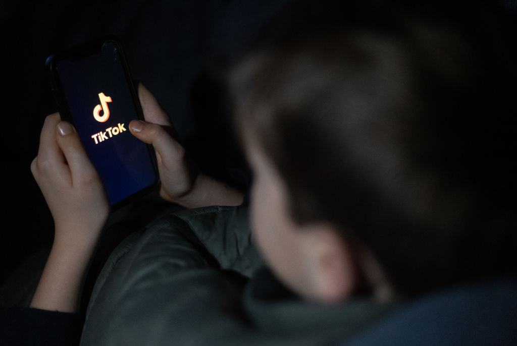 A 12-year-old boy looks at a smartphone screen displaying the TikTok logo on March 10, 2024, in Bath, England. (Photo by Matt Cardy/Getty Images)