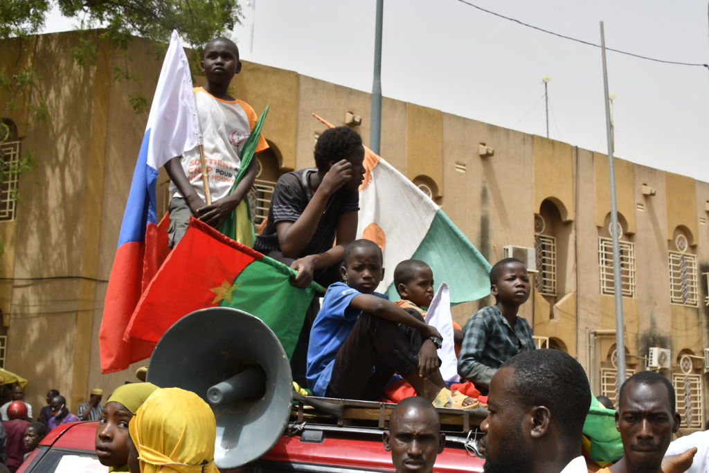 Young boys display flags of Niger, Burkina Faso, and Russia during a demonstration in Niamey, Niger, on April 13, 2024, advocating for the immediate departure of United States military deployed in northern Niger. (Photo by AFP via Getty Images)