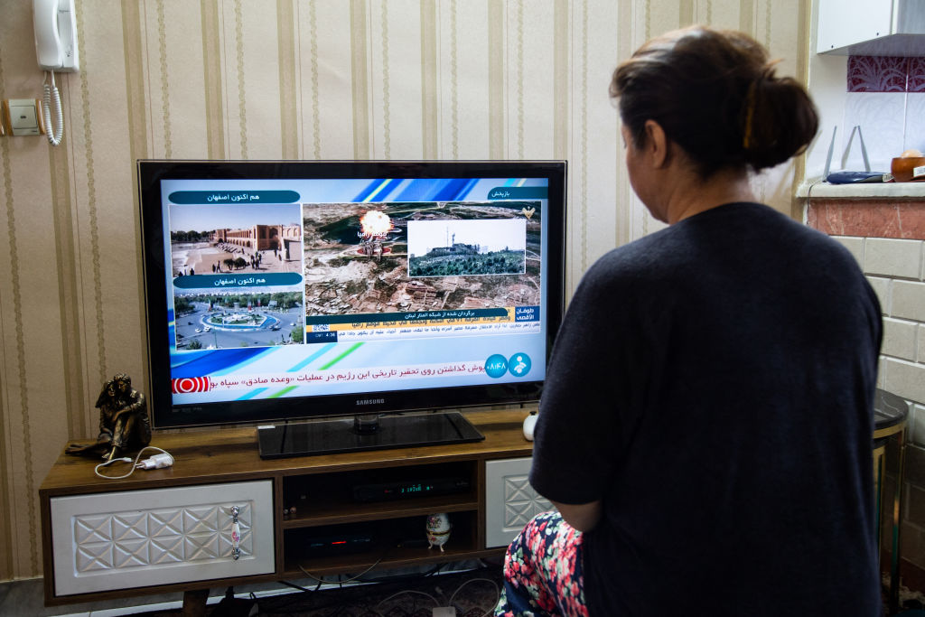 An Iranian woman in Tehran watches Iranian news after reports of "massive explosions" in central Isfahan province. (Photo by HOSSEIN BERIS/Middle East Images/AFP via Getty Images)