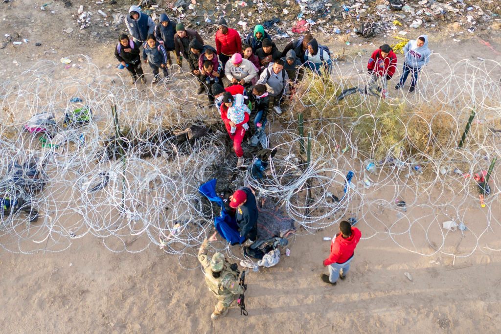 Texas National Guard troops stop immigrants trying to pass through razor wire after crossing the border into El Paso, Texas. Those who managed to get through the wire were then allowed to proceed for further processing by U.S. Border Patrol agents. (Photo by John Moore/Getty Images)