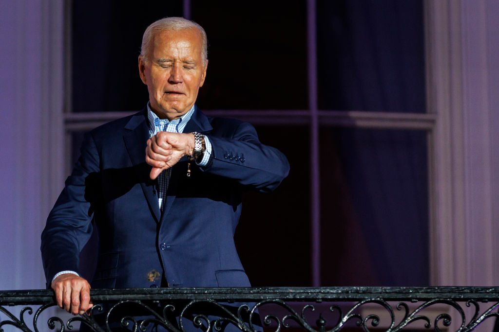 President Joe Biden checks his watch as he steps out onto the balcony of the White House to view the fireworks over the National Mall during a 4th of July event on the South Lawn of the White House on July 4, 2024. (Photo by Samuel Corum/Getty Images)