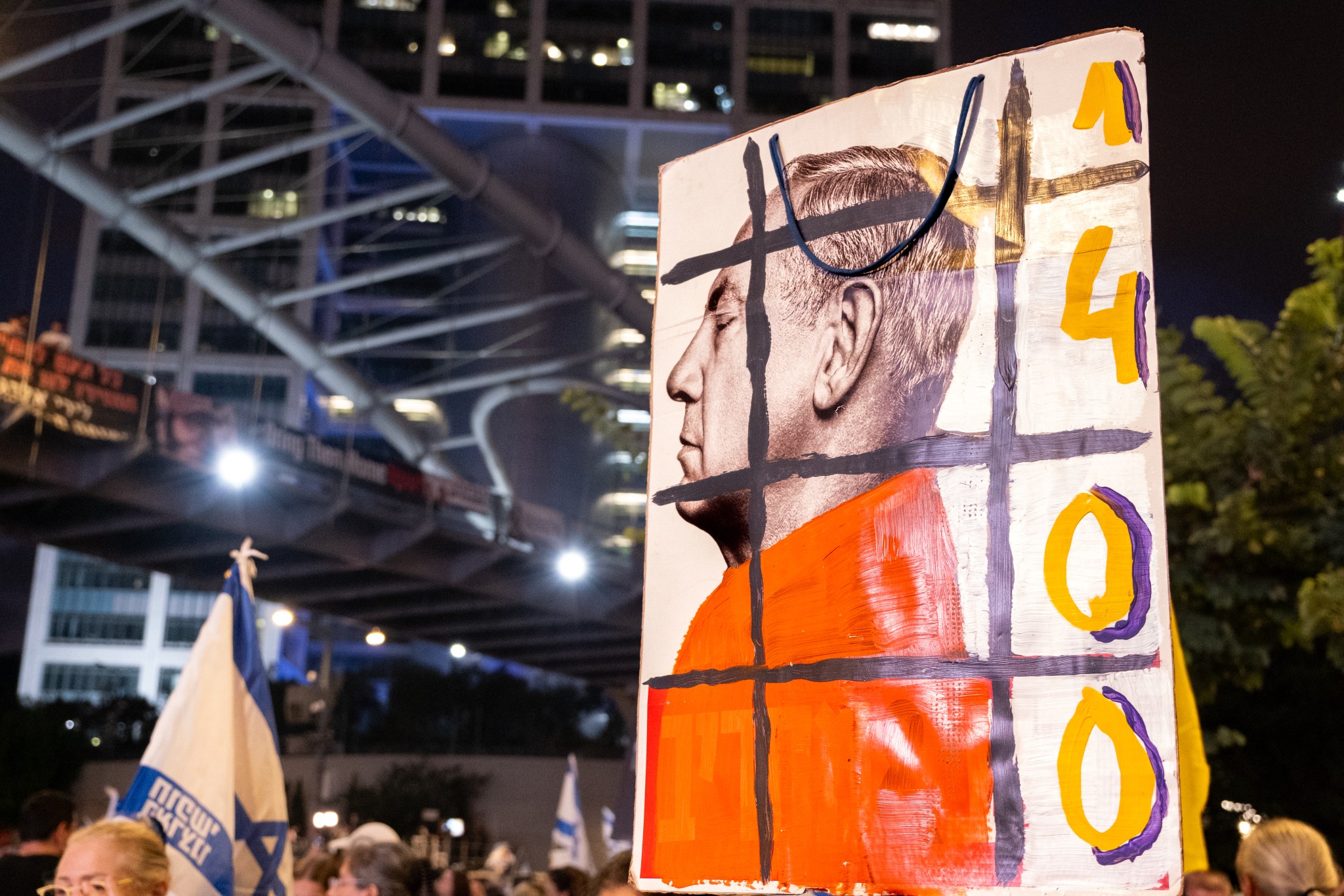 An anti-government protester in Tel Aviv carries a poster featuring Israeli Prime Minister Benjamin Netanyahu behind bars on September 7, 2024. (Photo by Charlotte Lawson.)