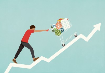 Man pushing shopping cart of groceries up line chart arrow