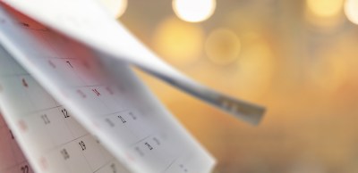 Close up white paper desk calendar with blurred bokeh background appointment and business meeting concept