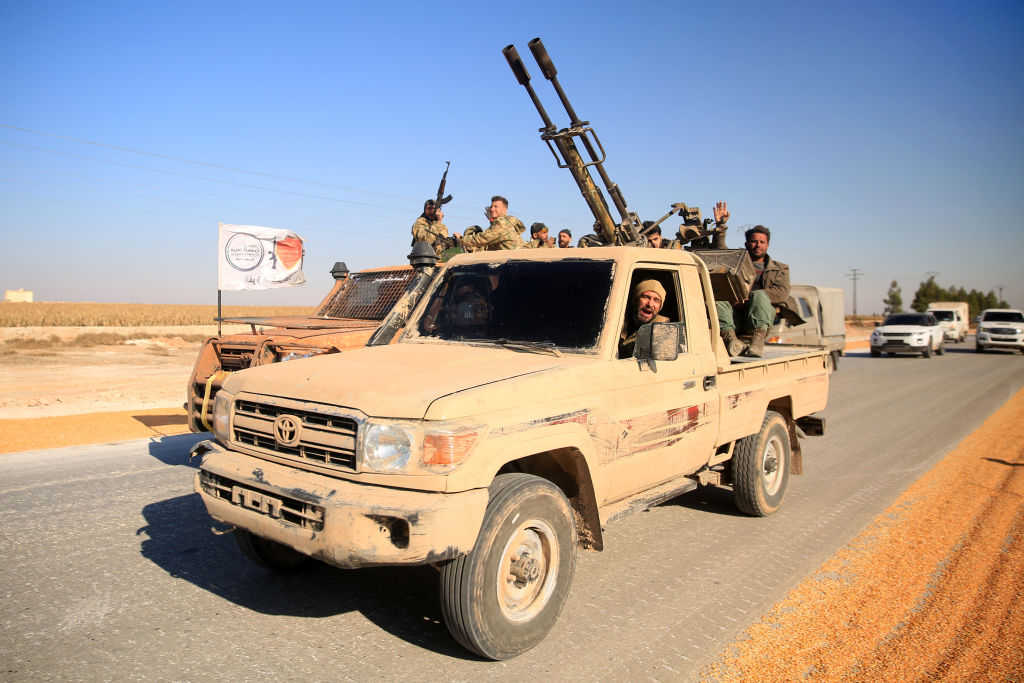 Syrian rebels ride military vehicles as they drive along a road in the eastern part of Aleppo province on December 1, 2024. (Photo by AREF TAMMAWI/AFP via Getty Images)