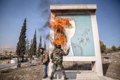 A man burns a picture of former Syrian president Bashar al-