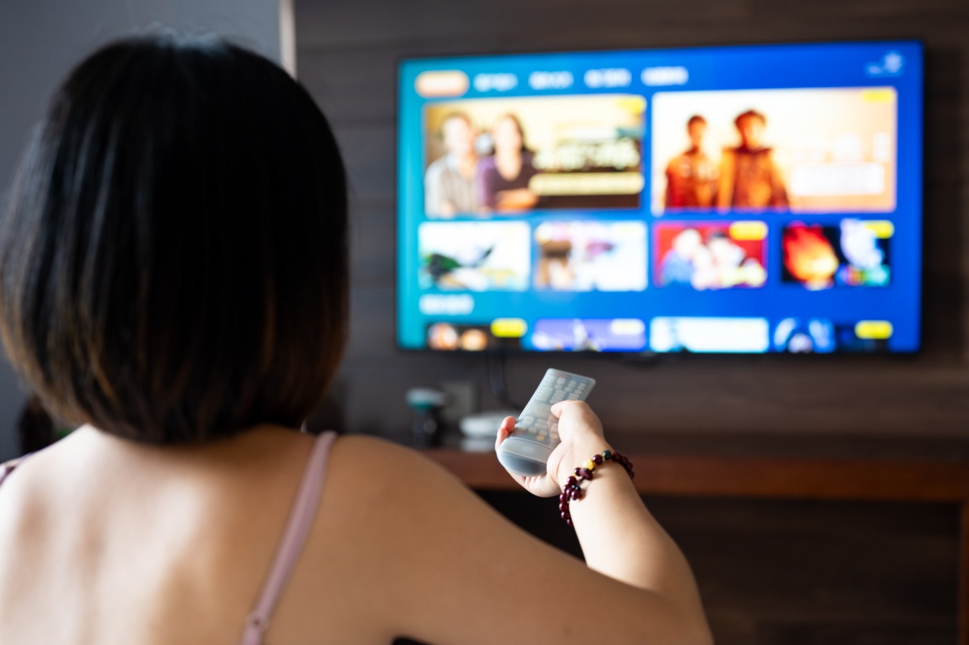Young woman watching 8K smart HDTV in hotel enjoying a travel and leisure lifestyle