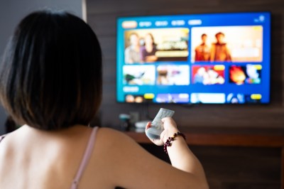 Young woman watching 8K smart HDTV in hotel enjoying a travel and leisure lifestyle
