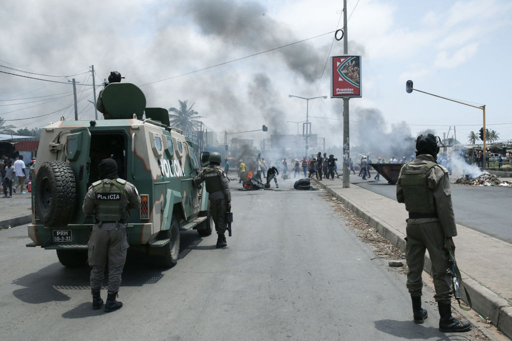 Mozambican police officers stand by as protesters burn tires during a demonstration against the government in Maputo on December 6, 2024. (Photo by AMILTON NEVES/AFP via Getty Images)