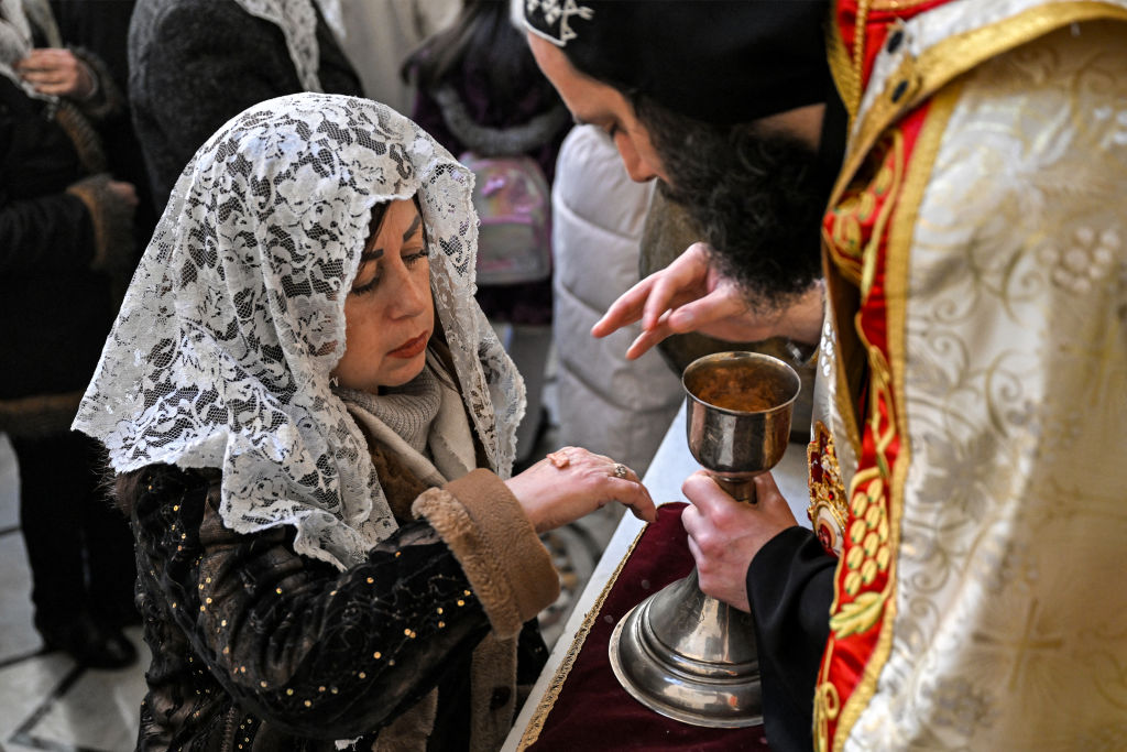 A worshipper receives communion at the Armenian Apostolic Church of Mar Sarkis (St. Sargis) in Bab Sharqi in the old city of Damascus on January 6, 2025. (Photo by LOUAI BESHARA/AFP via Getty Images)