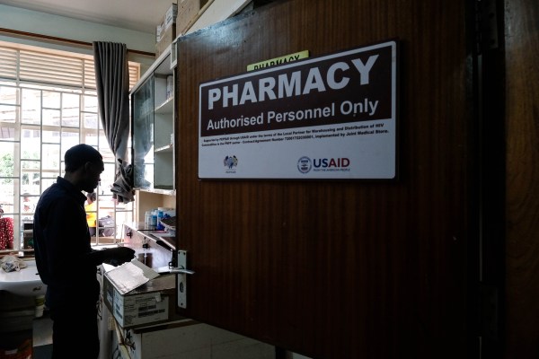 A pharmacist works beside a USAID poster at the AIDS support organization service center at Mulago Hospital on February 17, 2025, in Kampala, Uganda. (Photo by Hajarah Nalwadda/Getty Images)