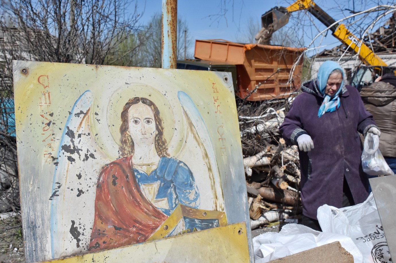 A woman walks next to a portrait of Christ as she collects what remains after a Russian rocket destroyed an Orthodox church on Easter night in Komyshuvakha in 2023. (Photo by Andriy Andriyenko/SOPA Images/LightRocket via Getty Images)