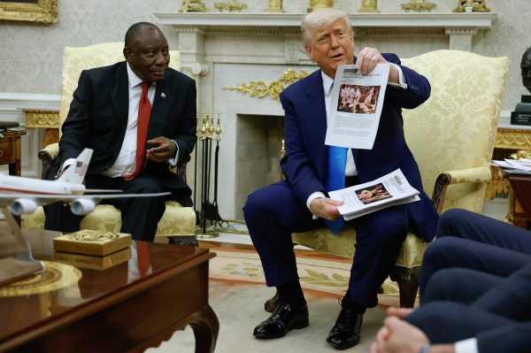 President Donald Trump holds up a printed article from 'American Thinker' while accusing South African President Cyril Ramaphosa of state-sanctioned violence against white farmers in South Africa during a press availability in the Oval Office on May 21, 2025. (Photo by Chip Somodevilla/Getty Images)
