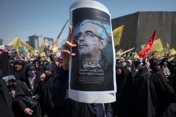 A veiled Iranian worshipper in Tehran holds a placard featuring a portrait of Chief of Staff of the Armed Forces of the Islamic Republic of Iran Major General Mohammad Bagheri, who was killed in Israeli attacks Friday, during a protest to condemn the attacks on Iran. (Photo by Morteza Nikoubazl/NurPhoto via Getty Images)