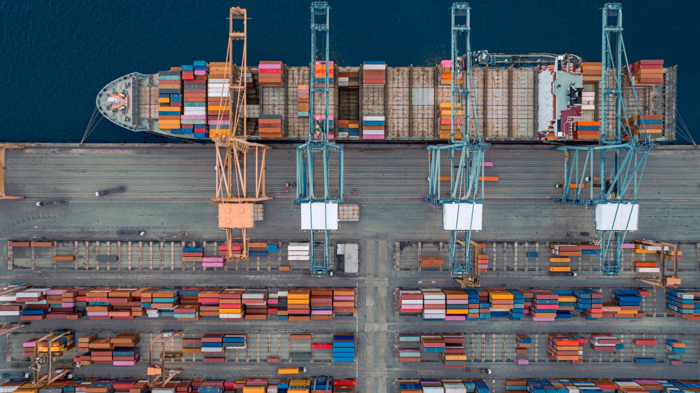 Cranes load containers on large container ship at a port. (Photo via Getty Images)