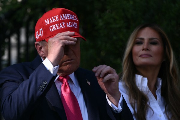Melania Trump looks on as President Donald Trump dons his MAGA hat before greeting members of the military and their families during the Military Family Picnic on the South Lawn of the White House in Washington, D.C, on July 4, 2025. (Photo by Brendan Smialowski/AFP/Getty Images)