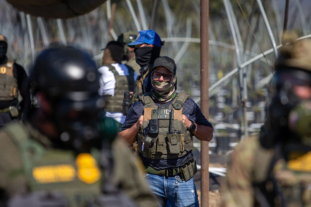 A U.S. Immigration and Customs Enforcement agent watches as Customs and Border Protection officers hold the line against protesters who responded to a Federal Immigration raid at Glass House Farms in Camarillo, California, July 10, 2025. (Photo by BLAKE FAGAN/AFP via Getty Images)