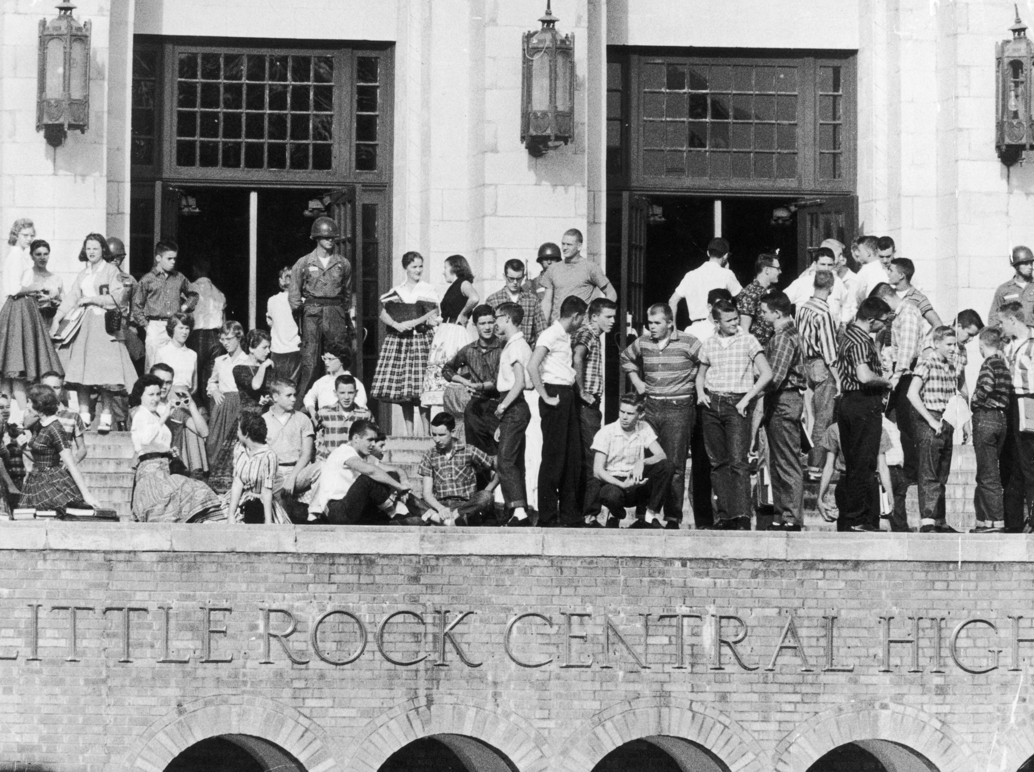 A view of National Guardsmen standing outside Little Rock Central High School and a large group of white students standing with them to prevent any African-American students from entering, during the first year of the desegregation of public schools in Arkansas, in September 1957. Nine black students were escorted into the school under federal protection later in the month. (Photo by Hulton Archive/Getty Images)