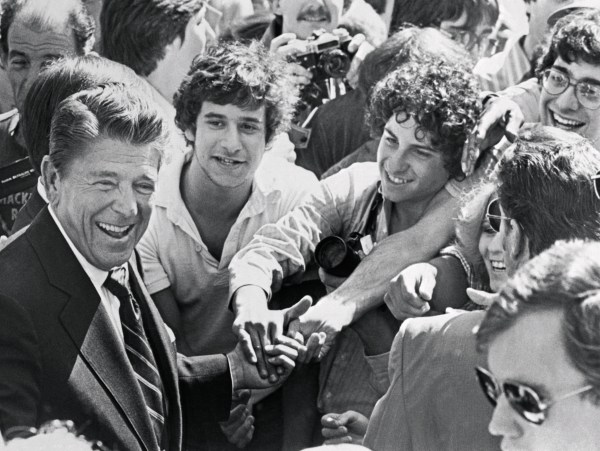 A smiling Ronald Reagan shakes hands with a group of young admirers all at the same time, as he walks among the crowd during a brief campaign stop. (Photo from the Bettmann Collection/Getty Images)