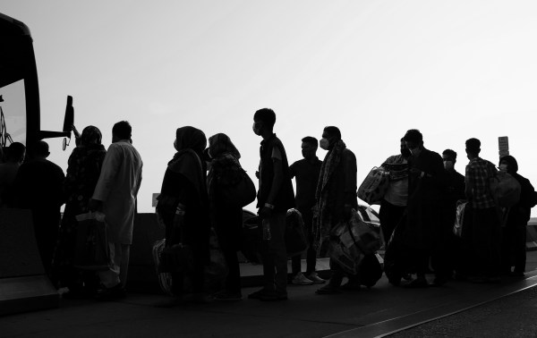 People evacuated from Kabul Afghanistan wait to board a bus that will take them to a refugee processing center at the Dulles International Airport on August 25, 2021, in Dulles, Virginia (Photo by Anna Moneymaker/Getty Images).