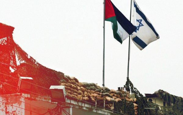 A Palestinian and Israeli flag fly side-by-side at the Beit Jala checkpoint in the West Bank on March 19, 2002. (Photo by PATRICK BAZ/AFP via Getty Images)